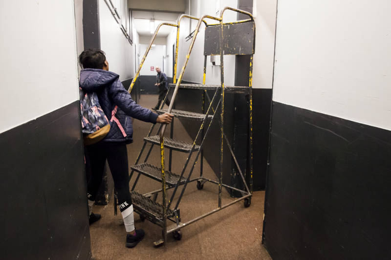 Brittany Jones pushes a set of portable stairs down the hallway of her storage unit.