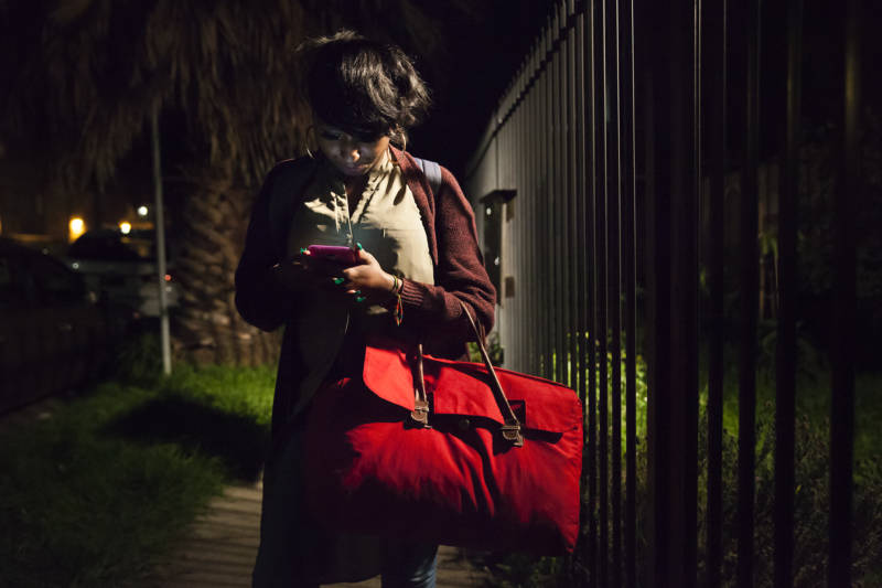 Brittany Jones checks her phone on her way to her grandmother’s house in Richmond. Her bright red bag carries all off her clothes she’ll need for the weekend before she goes back to her storage unit for more. 