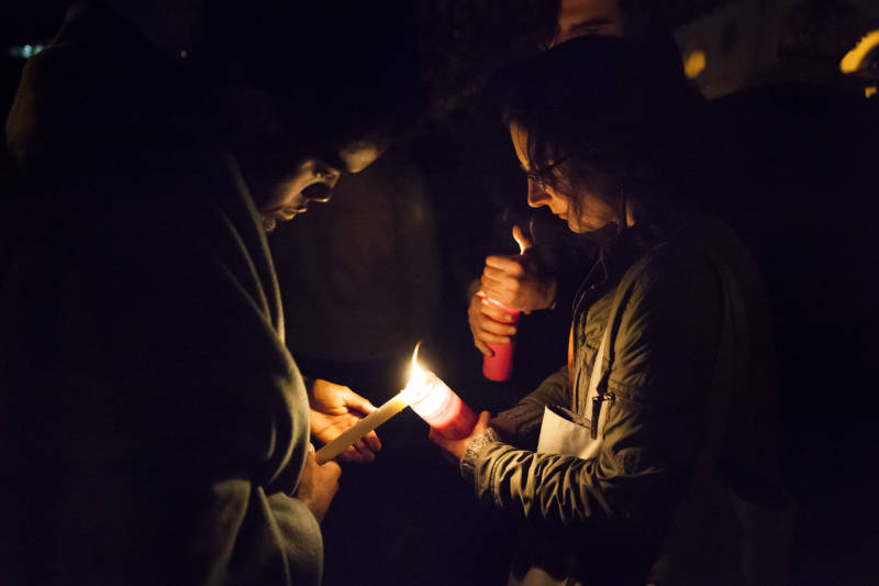 Mourners share candle flames during the vigil at Lake Merritt in honor of the victims of the Oakland warehouse fire on December 2.