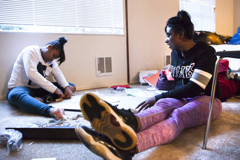Brittany Jones and her friend A’Dre’a Foster (left) work to put together a dining in Jones’ new apartment.