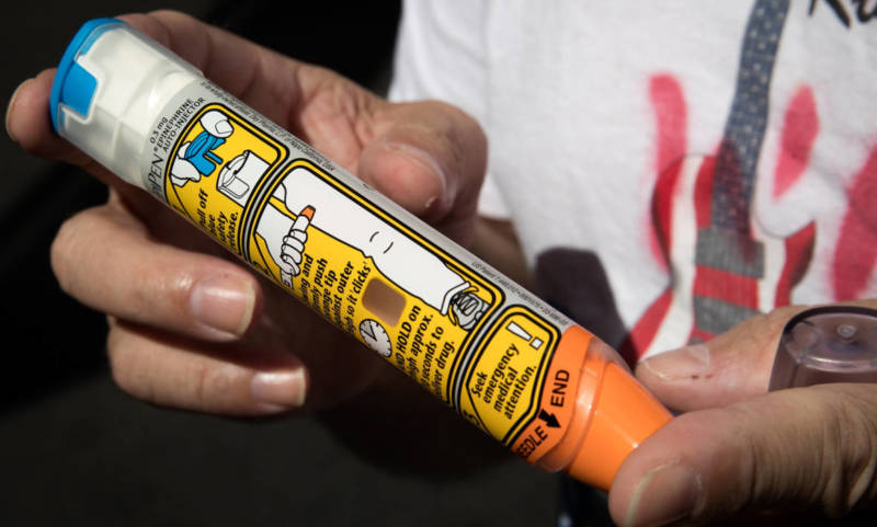 Timothy Lunceford Stevens, who suffers from autoimmune diseases and allergies, holds an EpiPen as he speaks to reporters during a protest against the price of EpiPens.