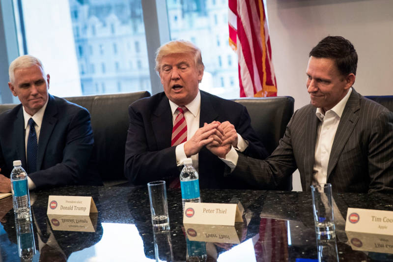 Mike Pence looks on as Donald Trump shakes the hand of Peter Thiel during a meeting with technology executives.