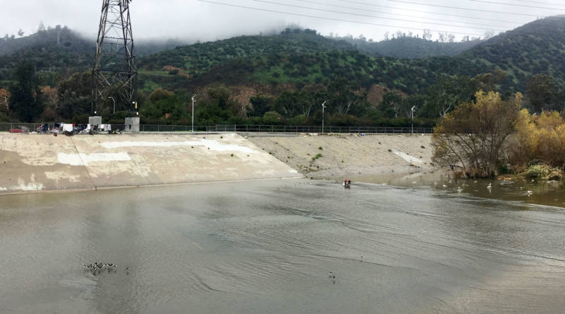 The L.A. River near Atwater Village is a flat, concrete flood control channel, designed to move water fast. Storm runoff can raise the river's level 10 feet and speed down the channel at 35 miles per hour. The islands where Wendy was living appear under the trees at right. Her present camp, at left, is approximately 50 feet higher up on the riverbank.