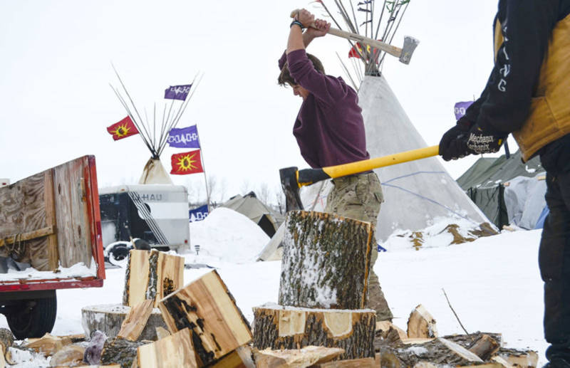 Jacob Chamberlain, 22, of Scotland chops firewood to use in fireplaces installed inside camp shelters. He plans to stay in North Dakota until the pipeline project is defeated.