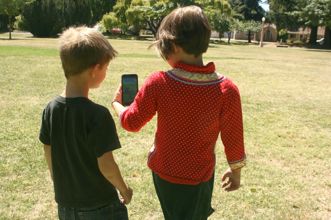 Two kids play Pokémon Go in the park. Note the absence of other players. That would soon change.
