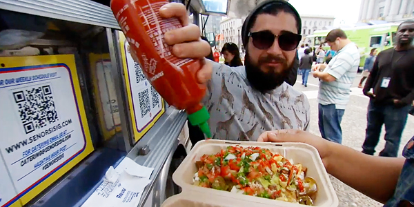 Spotted in the wild, a bearded millennial adds his millennial hot sauce of choice to a dish served out of a millennial-friendly truck. 