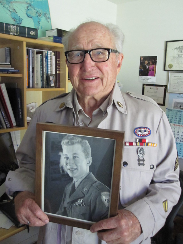 Don Foster poses with a photo of himself from World War II. (Scott Shafer/KQED)