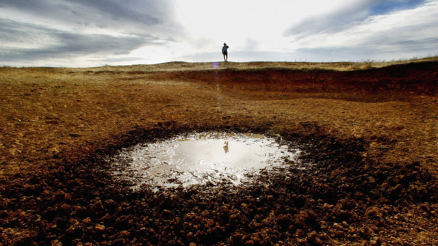 Farmer John Magill ponders a dried-up reservoir on his farm in Parkes, in 2006. (Ian Waldie/Getty Images)