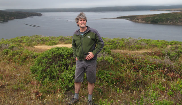 College of Marin biology professor Joe Mueller on a ridge overlooking Home Bay, part of Drake's Estero. The oyster farms are visible in Home Bay. (Cy Musiker/KQED)