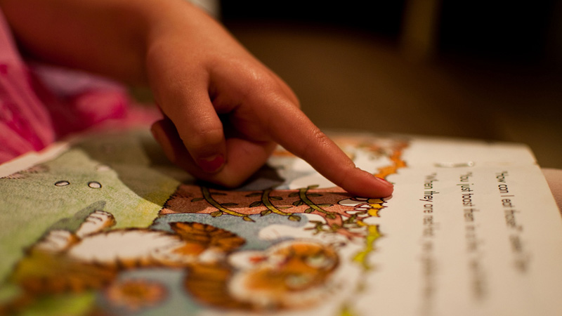 Kindergartener learning to read a book (Holtsman/flickr)