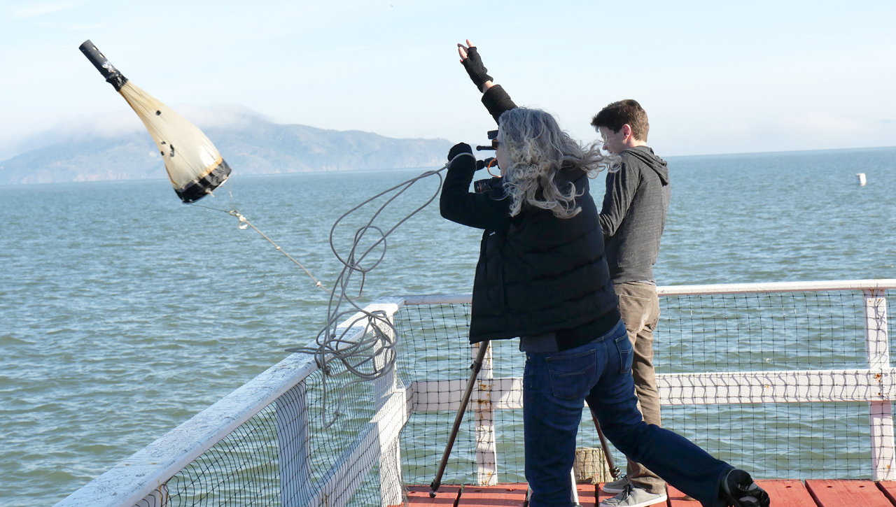 Melissa Dubose of the Romberg Tiburon Center casts her plankton net, with producer Josh Cassidy looking on (Mallory Pickett/KQED)