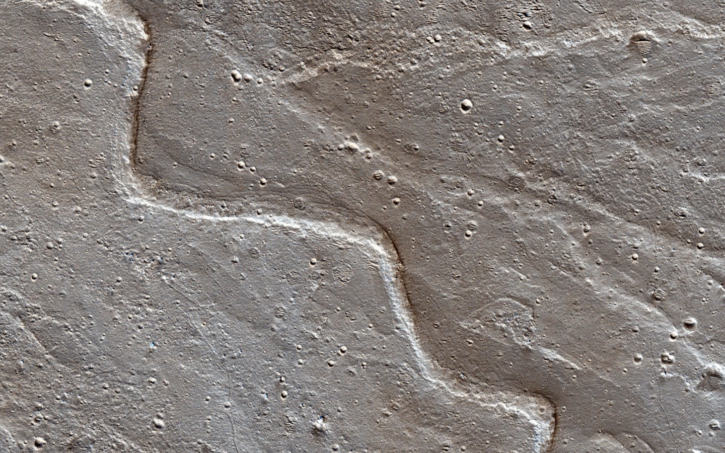 The sinuous ridges on the Orson Welles bajada mark the paths water took as it flowed into this crater. The sinuosity of the ridges tells us something about the speed of the water flow. Fast-moving flows tend to be straighter than slow-moving. (NASA/JPL-Caltech/Univ. of Arizona)