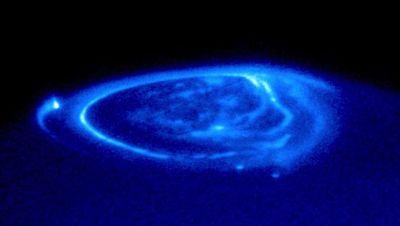 Auroras surround Jupiter's North Polar region, revealing the gas giant's powerful magnetic field emerging from within. 