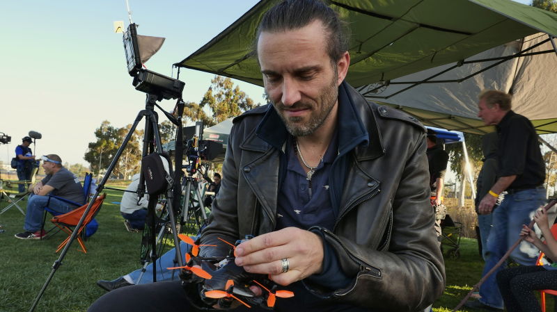 A drone racing pilot adjusts his drone before the start of a race. 