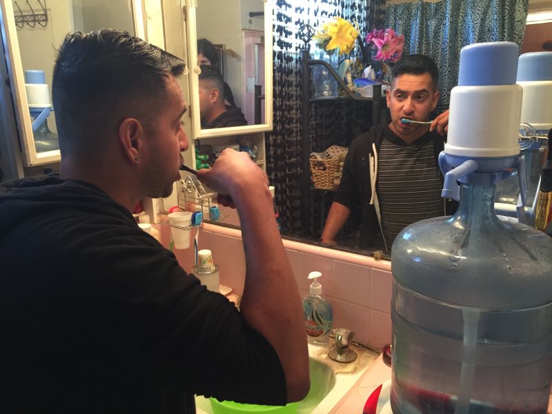 Guillermo Lopez brushes his teeth using a portable water jug. He and his mother lived without running water for nine months after their well went dry in rural Fresno County.
