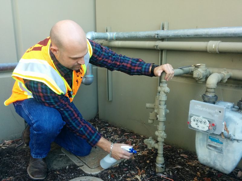 A PG&E crew member uses soap to identify the exact location of a gas pipeline leak.