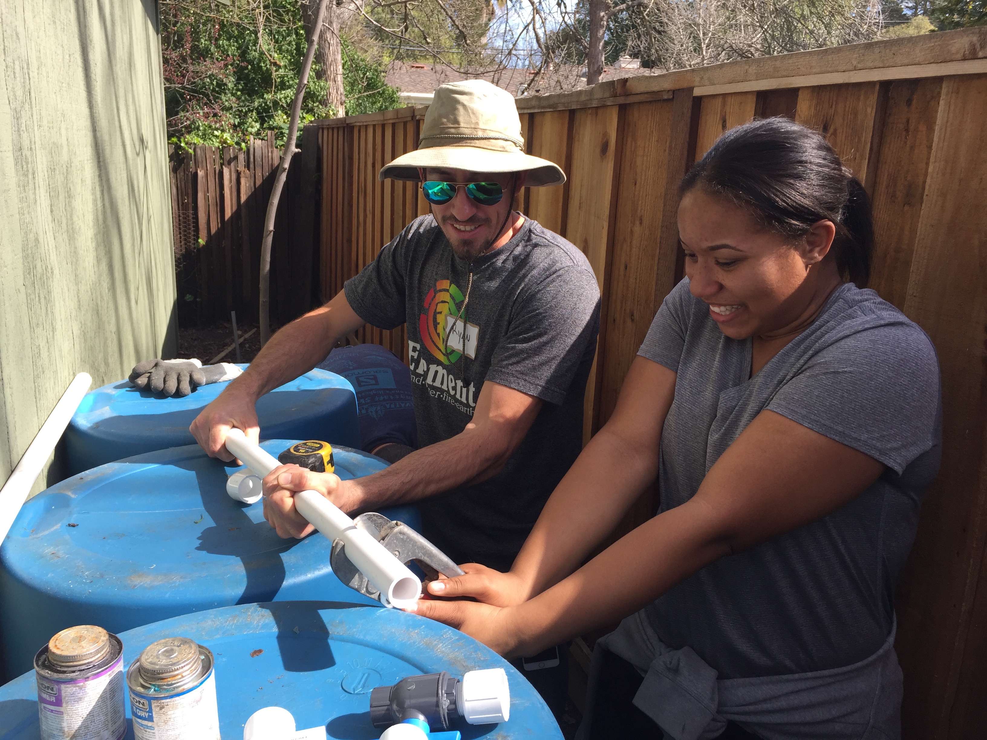 Landscape designer Ryan Kelsey shows Zakeisha Plummer how to cut PVC piping for a backyard rainwater capture system in Walnut Creek.