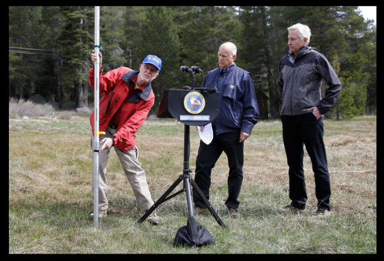 Governor Jerry Brown looks on as last April's snow survey is conducted on barren ground along Highway 50, near Echo Summit.