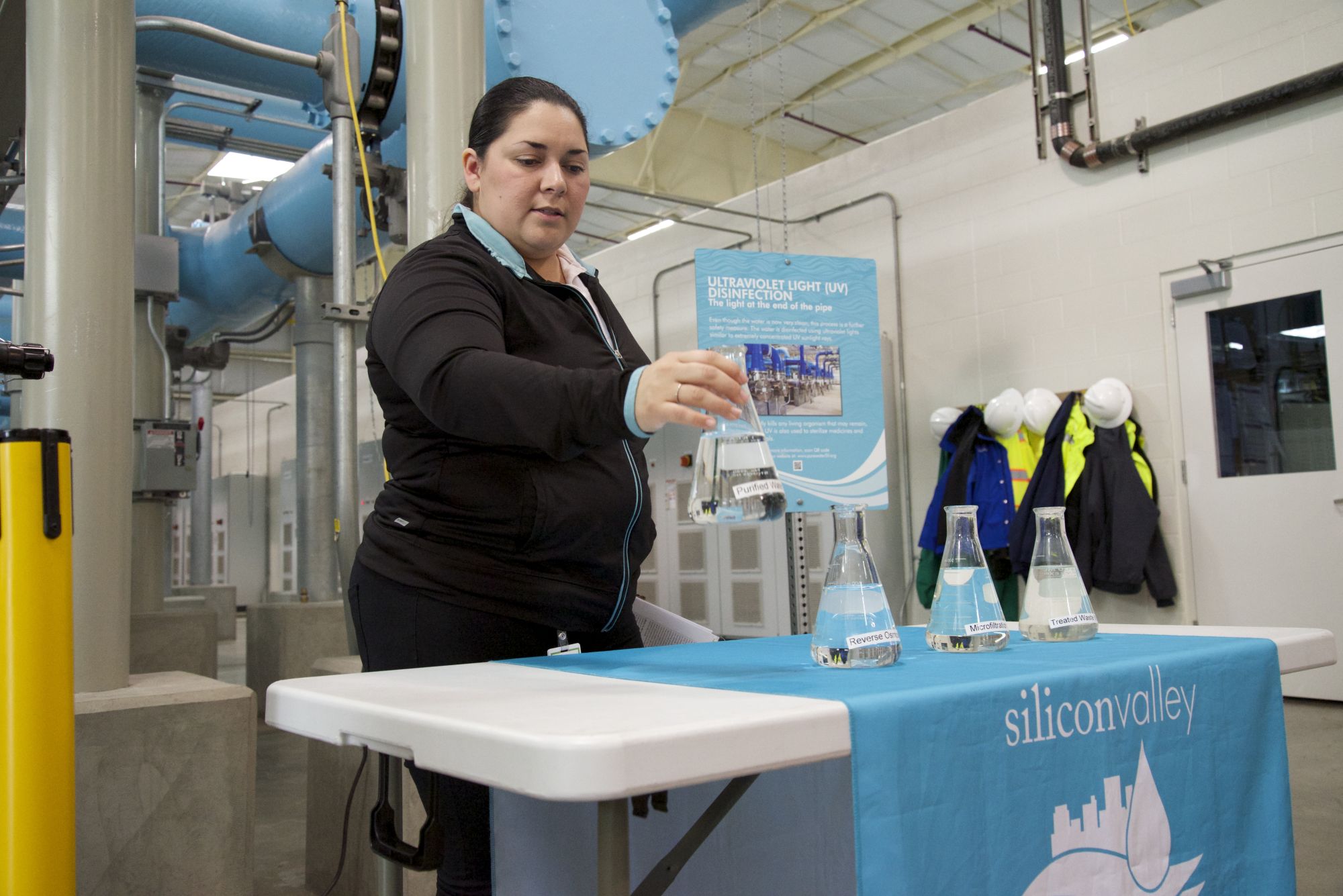 A tour guide at the Silicon Valley Advanced Water Purification Center in San Jose, California, shows off a container of treated water. Santa Clara Valley Water District hopes to expand its water reuse program. 