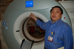 Changvang Her demonstrates how a CAT Scan machine at Mercy Medical Center plays an automated recording of his voice giving directions in Hmong -- for when he's not around to translate.