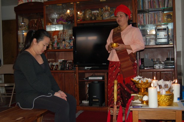 A Hmong shaman blesses a pregnant woman during a traditional healing ceremony.