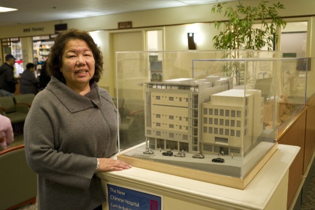 Chinese Community Health Plan CEO Brenda Yee shows visitors a model of the new Chinese Hospital building. "We know where our culture, we know where our foundation, where everything started," she says. "We won't lose our identity." (Marcus Teply/KQED)