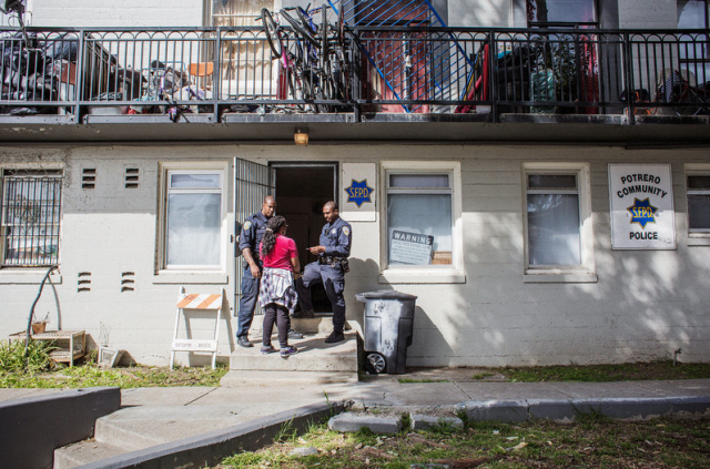 Uzuri Pease-Greene talks with two police officers in the public housing complex in San Francisco where she lives. (Talia Herman/NPR)