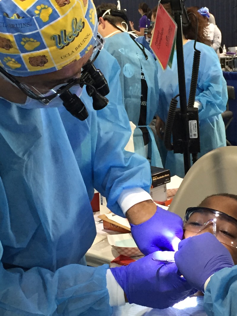George Maranon, an oral surgeon from Encino, is extracting a tooth from a young boy who already has diseased gums. 