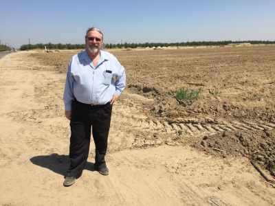 Respiratory therapist Kevin Hamilton stands near an unplanted field on a dusty farm road west of Fresno.