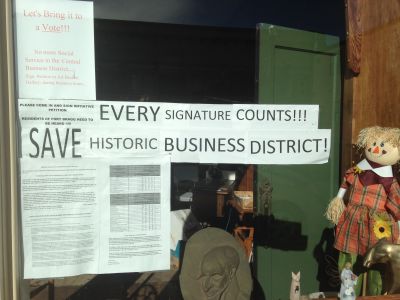 Signs in the window of a downtown Fort Bragg business urge residents to sign a petition for a ballot measure that would prohibit social service agencies in the downtown area. 