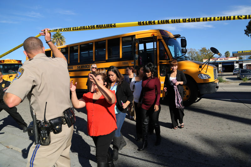 Employees and other people are evacuated by bus from the site of a mass shooting at the Inland Regional Center in San Bernardino.