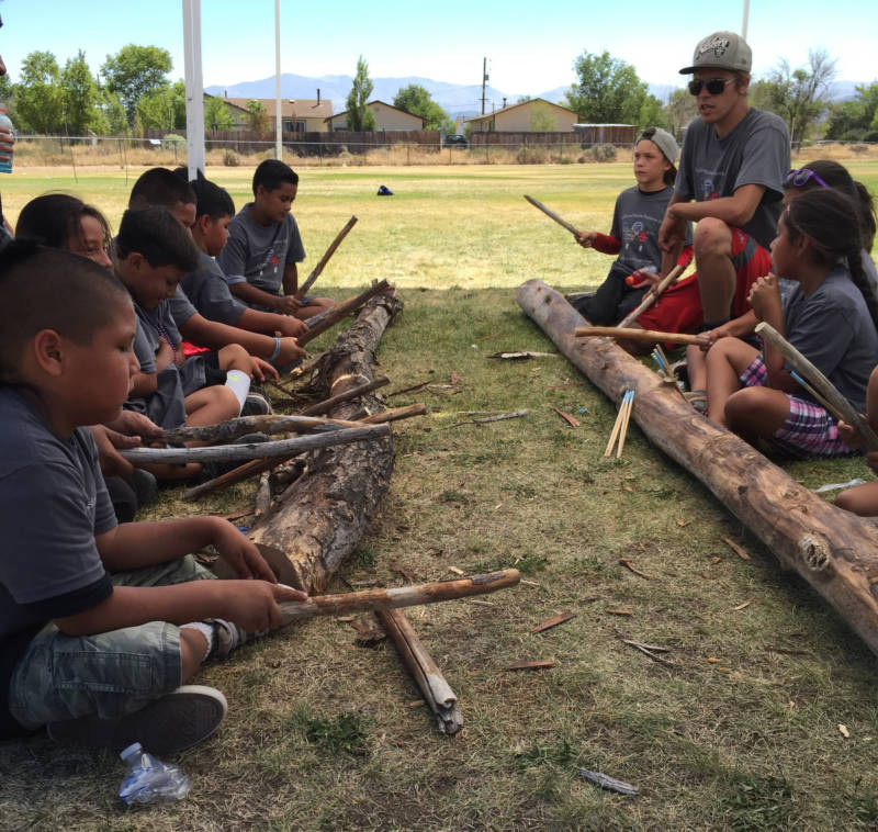 Herman Fillmore (upper right) teaches young Washoe kids how to play the game Hinoyowgi in Gardnerville, Nevada. This game incorporates rhythm and song.