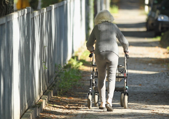 An elderly woman pushing her walker.
