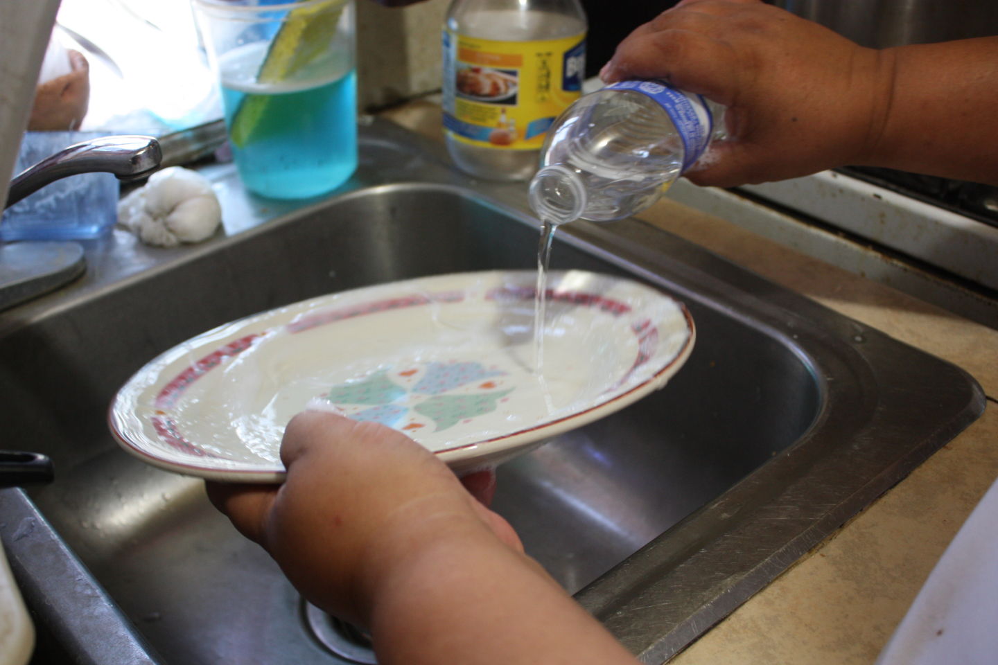 Without a working faucet, Maria Medina washes dishes with little 16-ounce water bottles. She says each dish requires about half a bottle.  Kerry Klein/KQED