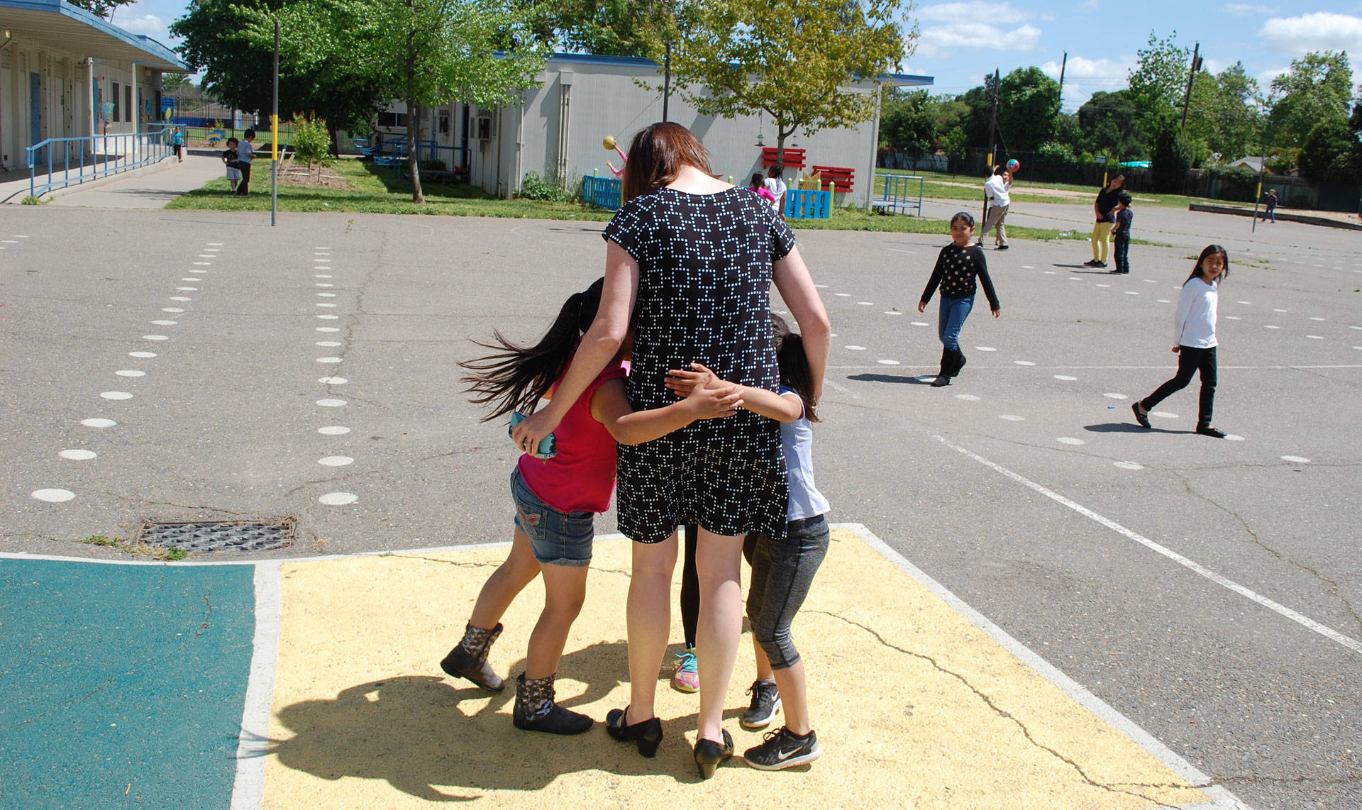Bethany Coburn, a social worker and coordinator of the Student Support Center at Oak Ridge Elementary, receives a group hug from students on campus. Gabriel Salcedo/KQED