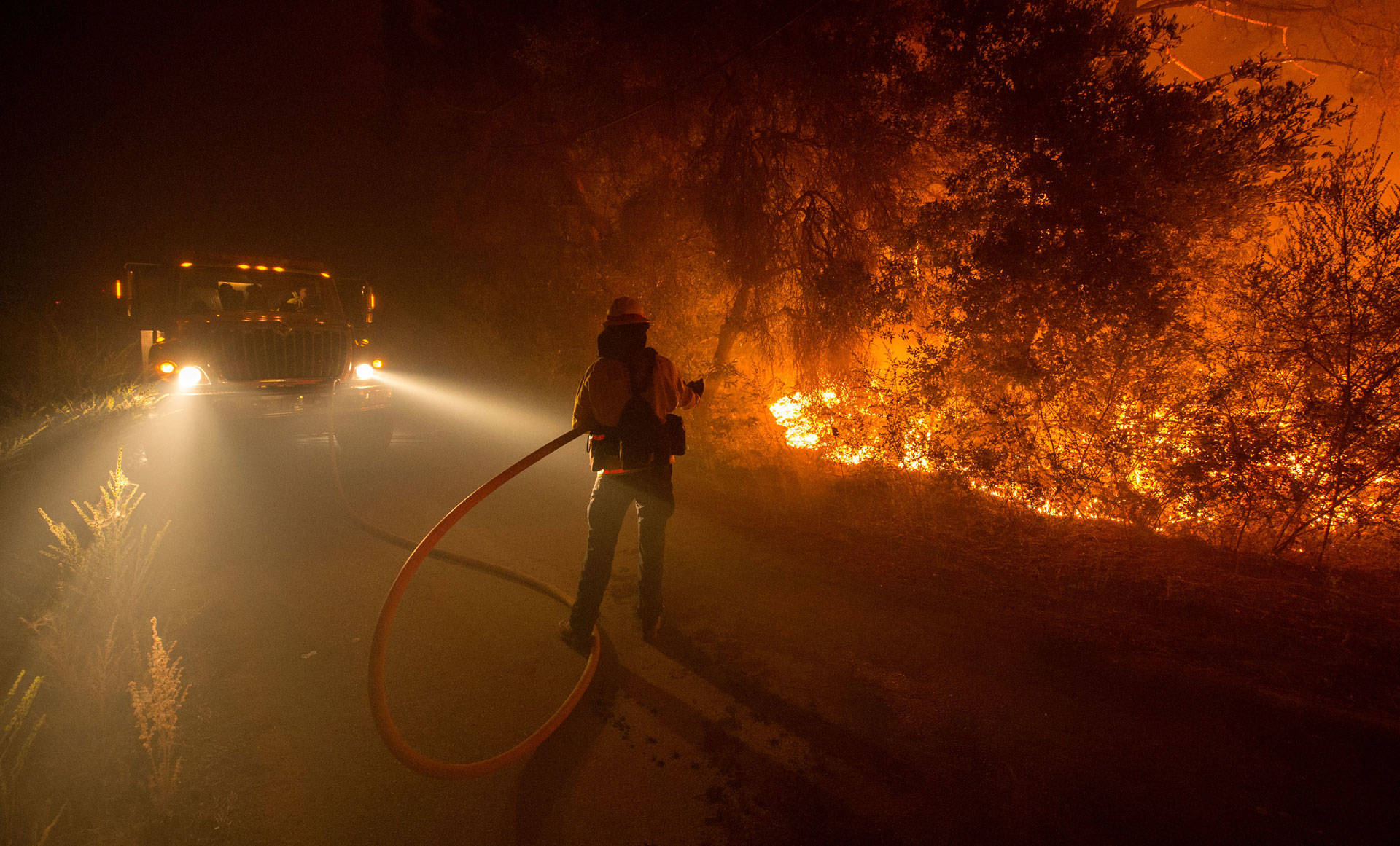 A firefighter douses flames as they approach a road in the Santa Cruz Mountains near Loma Prieta on Sept. 28, 2016. Josh Edelson/AFP/Getty Images