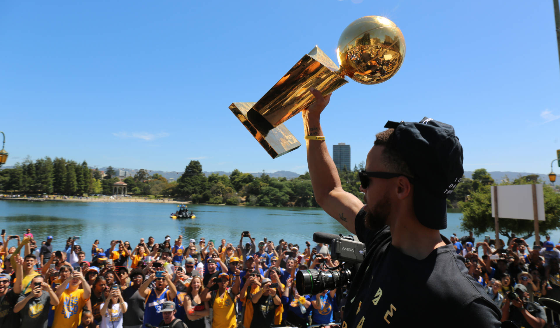 Stephen Curry lifts the NBA Championship trophy to Warriors fans lining Lake Merritt. Adam Grossberg/KQED