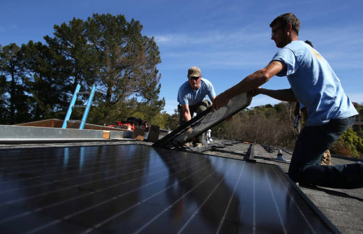 Workers install solar panels on the roof of a home in San Rafael.