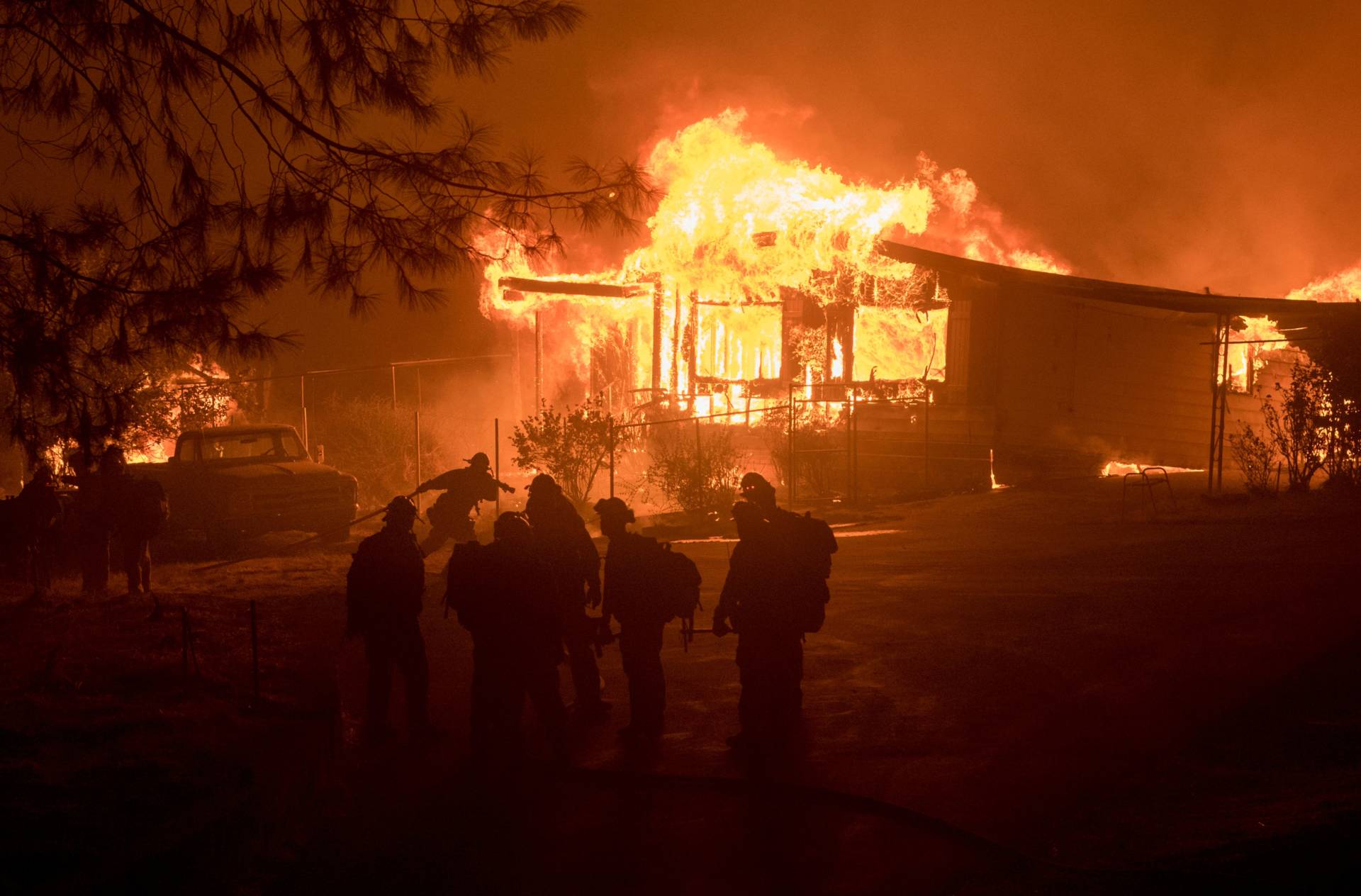 A firefighter carries a hose as a house burns Saturday night east of Oroville. The home was one of 17 structures destroyed by the Wall Fire, which broke out in rural Butte County on Friday. Josh Edelson/AFP-GettyImages
