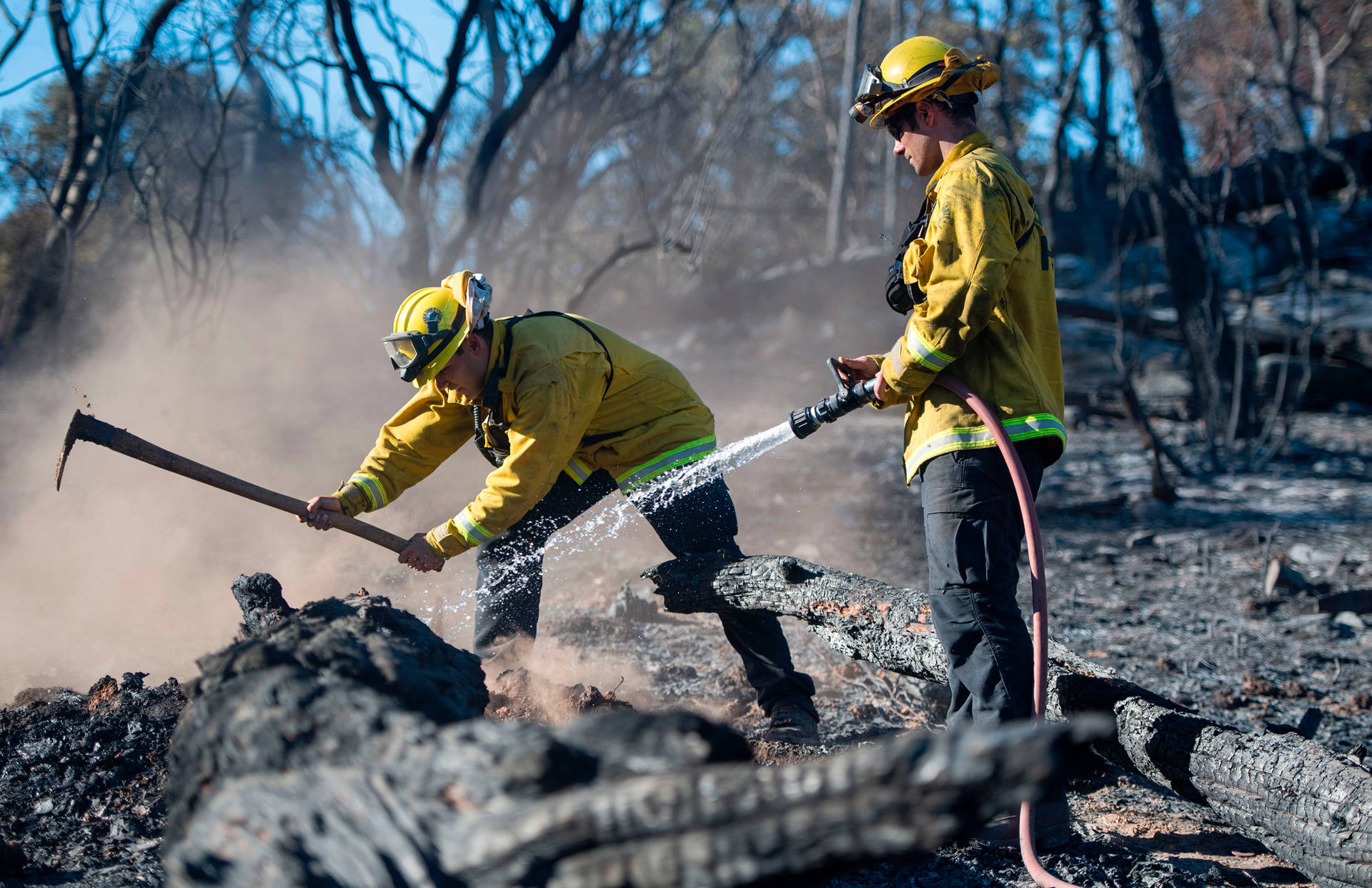 Bryce Briare (R) and Mike Manibusan (L) with the Marin County Fire Deptartment work on a smoldering hot spot as firefighters continue to build toward containment of the Wall Fire in Oroville on July 10, 2017.  JOSH EDELSON/AFP/Getty Images