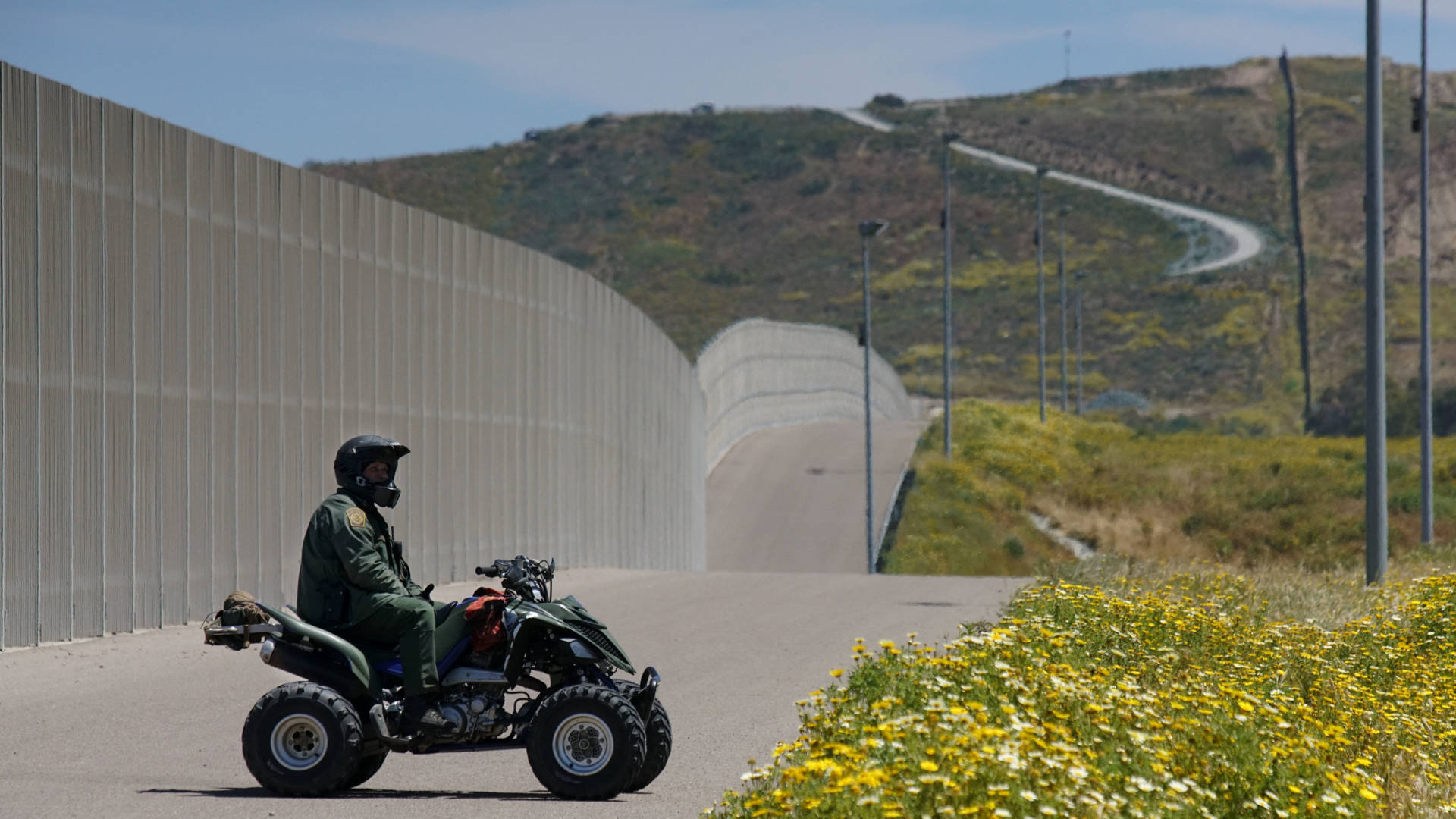 A Border Patrol agent keeps watch over the U.S.-Mexico border fence just south of San Diego earlier this year. The Department of Homeland Security announced Tuesday that it would waive environmental and other laws to expedite its construction of barriers and roads in the region. Sandy Huffaker/AFP/Getty Images