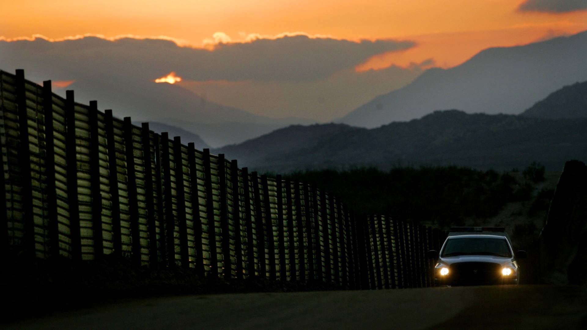 A Border Patrol vehicle rides beside an already existing portion of the wall along the U.S.-Mexico border south of San Diego. Sandy Huffaker/Getty Images