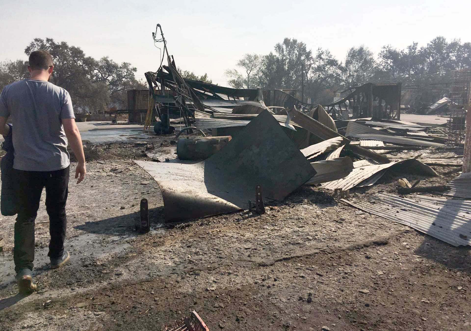 Ned Russell walks through the charred remains of his farm. Tonya Mosley/KQED