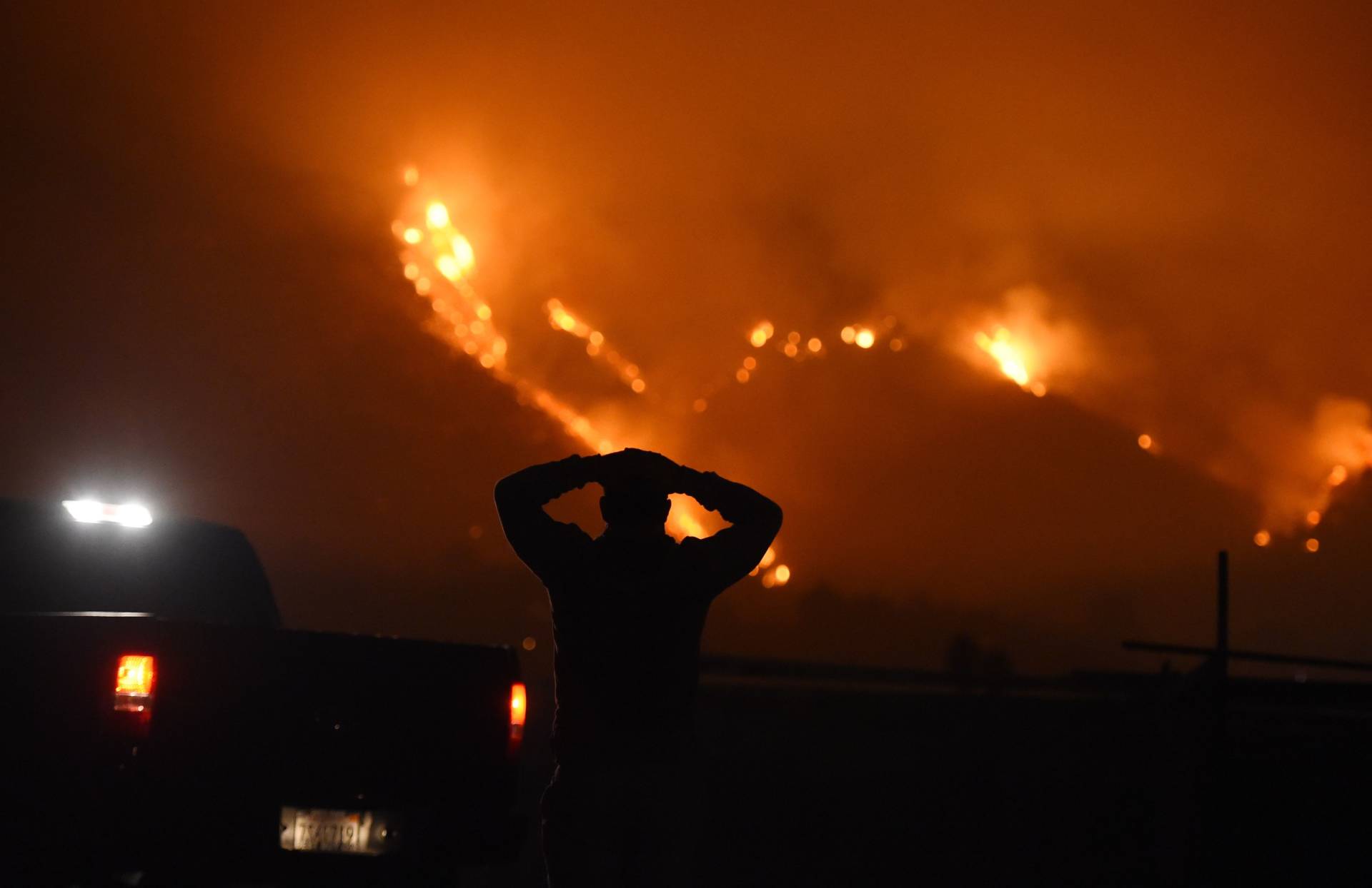 A man watches the Thomas Fire in the hills above Carpinteria on Dec. 11, 2017. The fire, burning in California's Ventura and Santa Barbara counties, has consumed more than 230,000 acres over the past week, making it the fifth-largest fire in state history. Robyn Beck/AFP/Getty Images