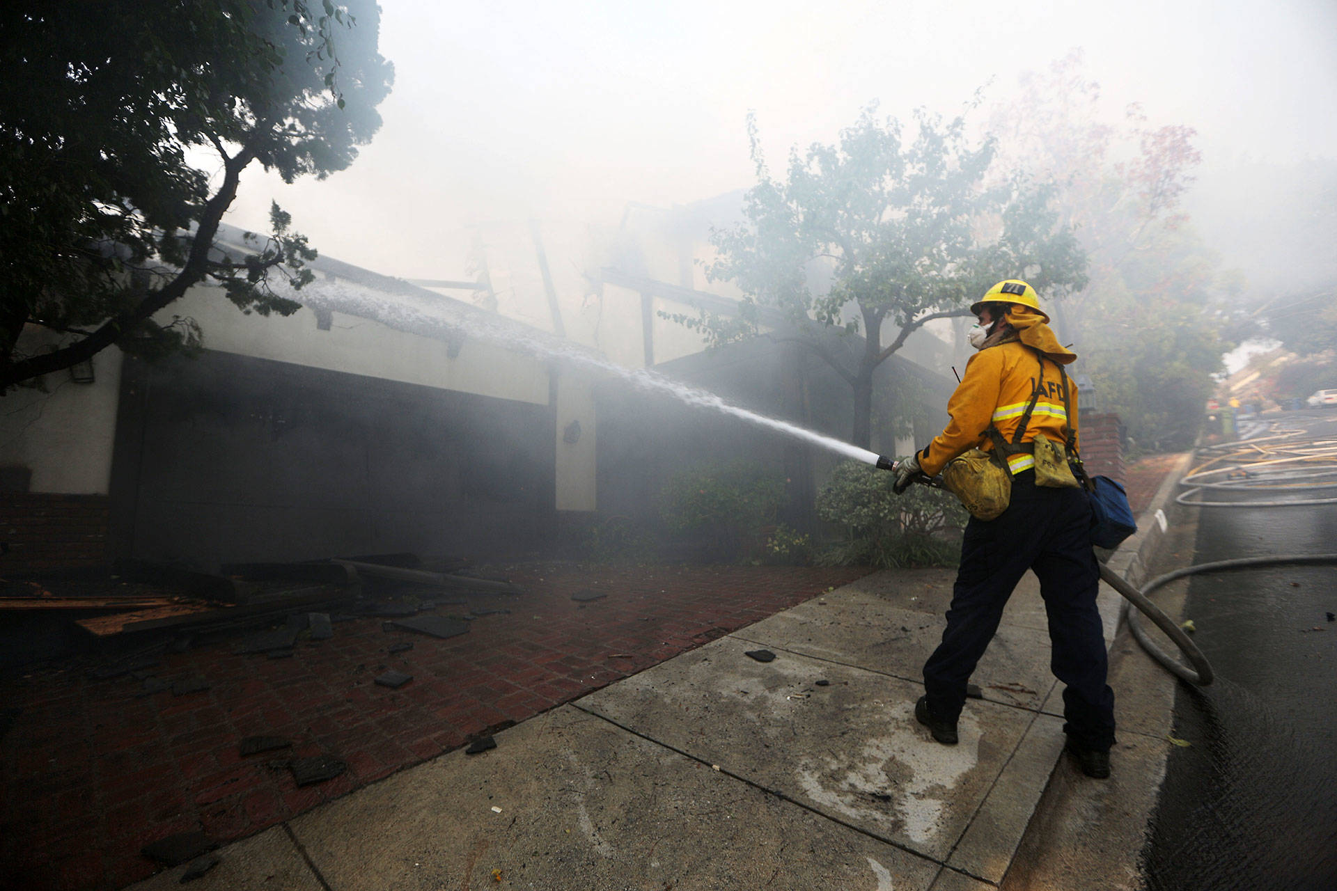 A firefighter sprays water on a burning home in the wealthy Bel Air neighborhood during the Skirball Fire on Dec. 6, 2017. Mario Tama/Getty Images