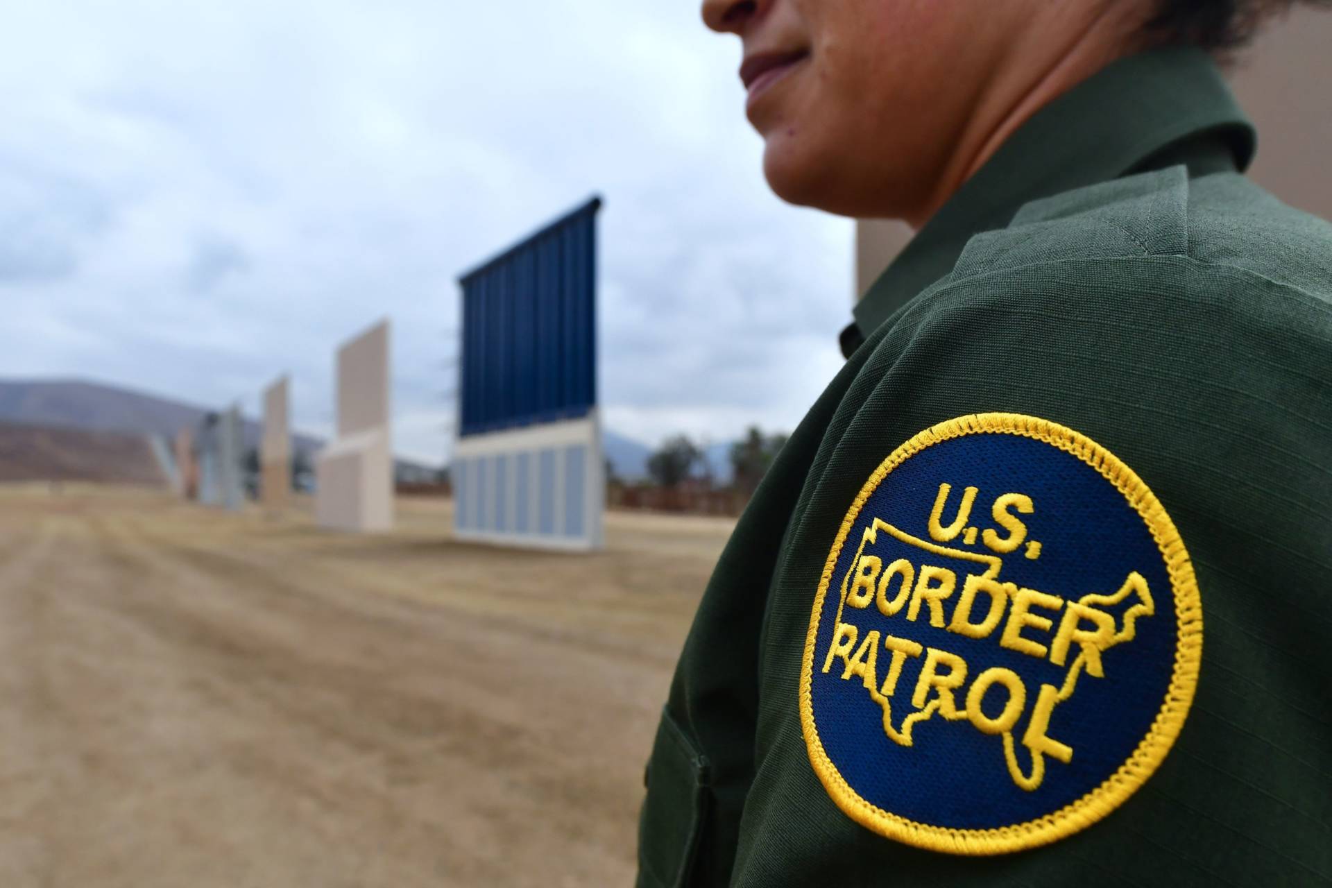 A U.S. Border Patrol officer stands near prototypes of President Trump's proposed border wall in San Diego. Border officers apprehended 310,531 people for being in the country illegally in fiscal 2017, a 25 percent decrease from the year before. Frederic J. Brown/AFP/Getty Images