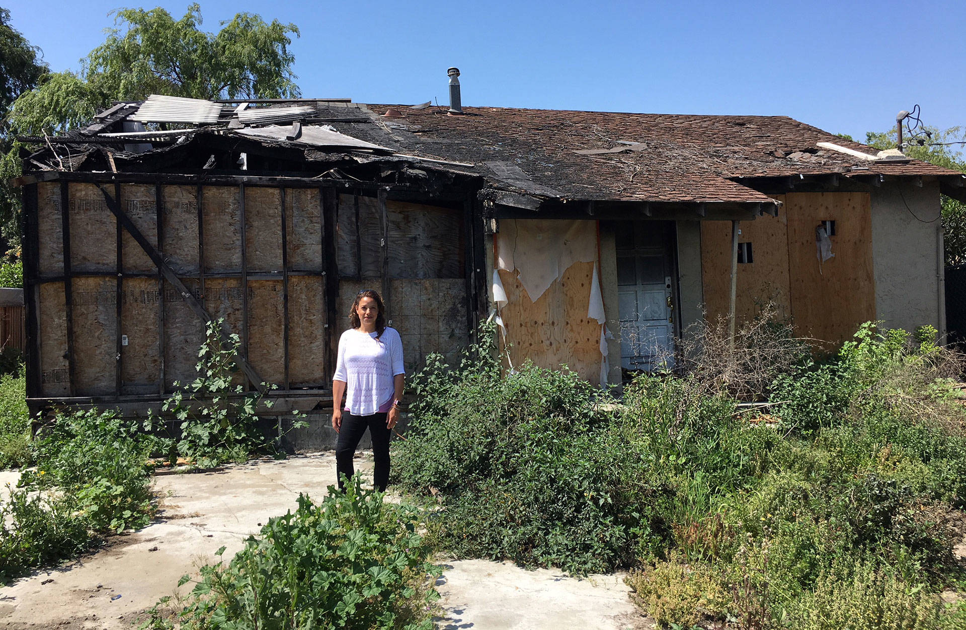 San Jose Realtor Holly Barr stands outside the burned-out house she sold for more than $900,000. Matt Levin/CALmatters