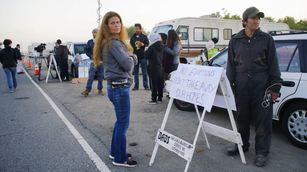 Amber Whitson and Pamela Benfante stand on the dirt lot next to Marina Boulevard on Memorial Day, waiting for Berkeley police to evict the vehicle community. Before 6 a.m. on that morning, a group of activists came to support the RV encampment and used their own vehicles to block the eight RVs still parked on the dirt lot.  Christian Torres/KQED