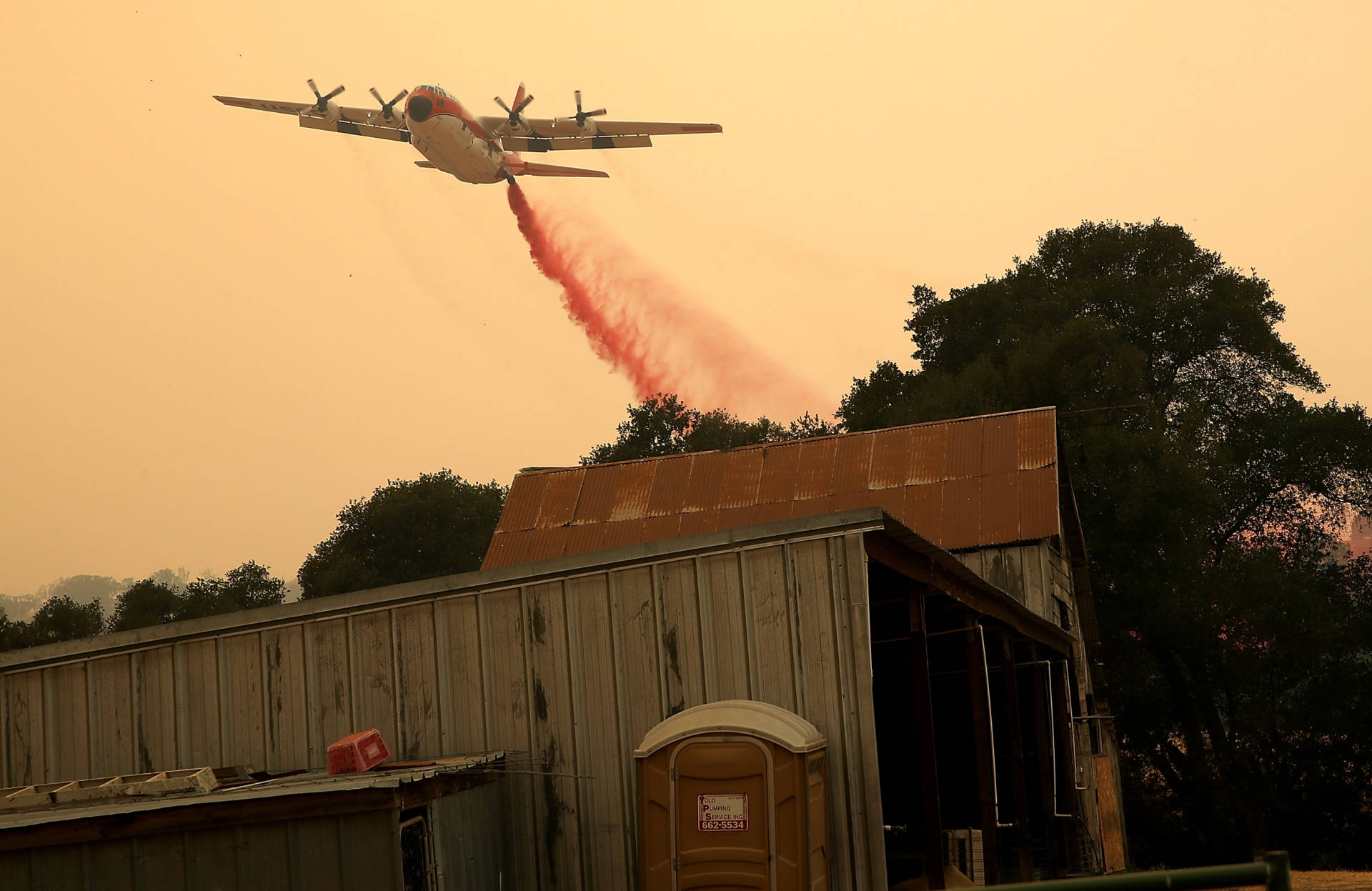 A firefighting air tanker drops fire retardant near a structure ahead of the County Fire on July 2, 2018, in Esparto. Justin Sullivan/Getty Images