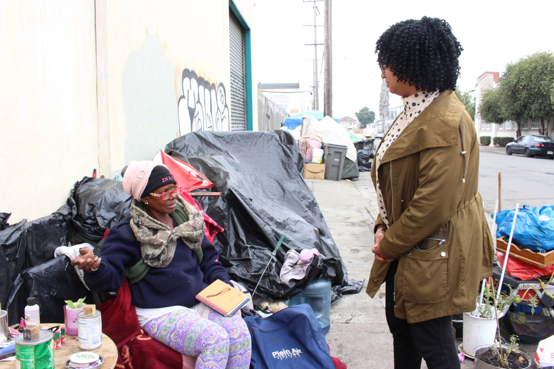Homeless advocate Candice Elder, 34, checks in with Dorothy Smith, 65, at an encampment in Oakland on Aug. 24, 2018. Smith, who raised her children in the city, said her disability benefits are not enough to afford housing. 'It just don’t support me,' she said.
 Farida Jhabvala Romero/KQED